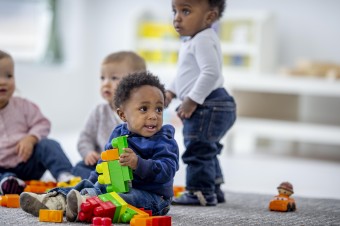 Image of four toddlers playing with colourful blocks.