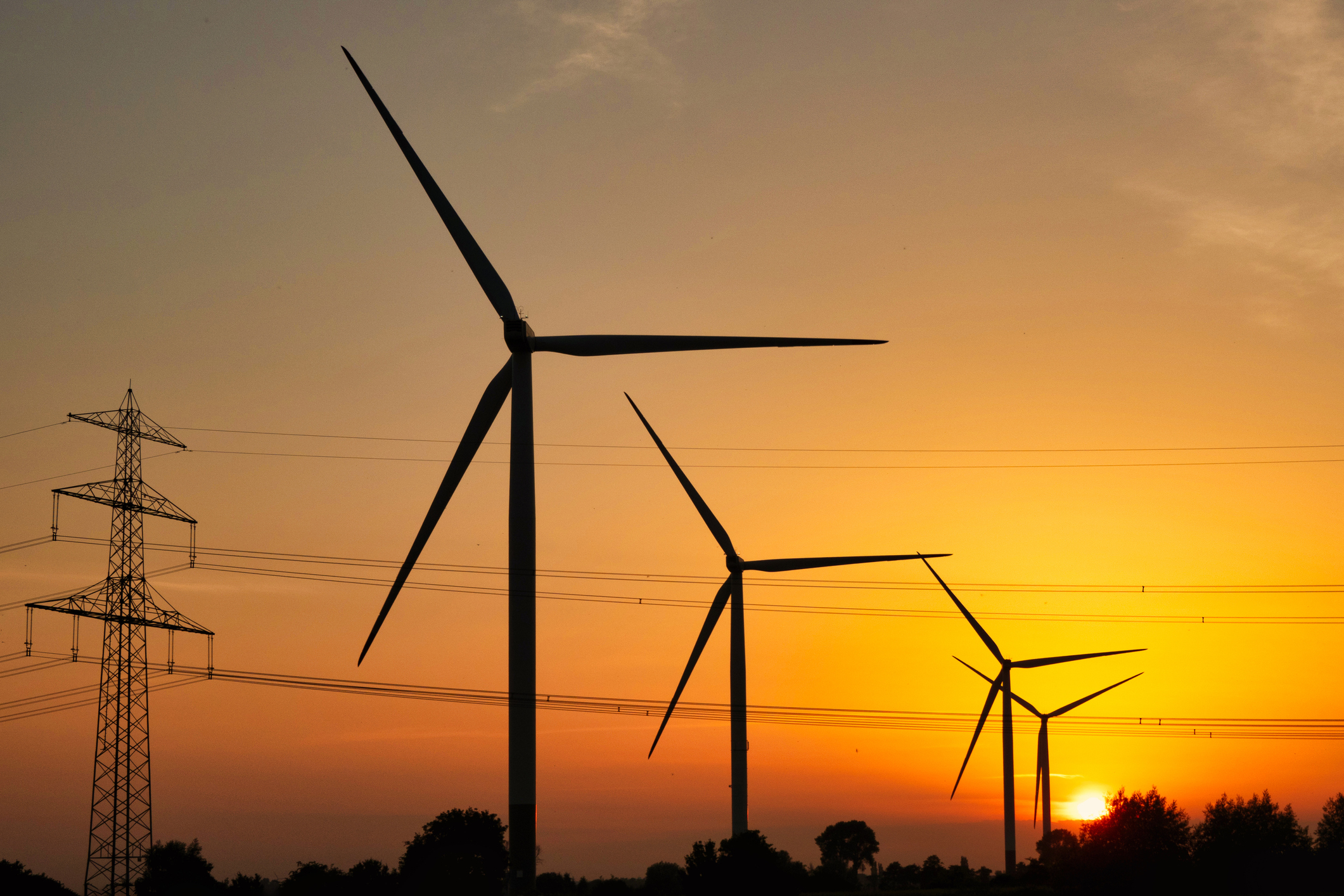 windmills and powerlines against the background of the setting sun