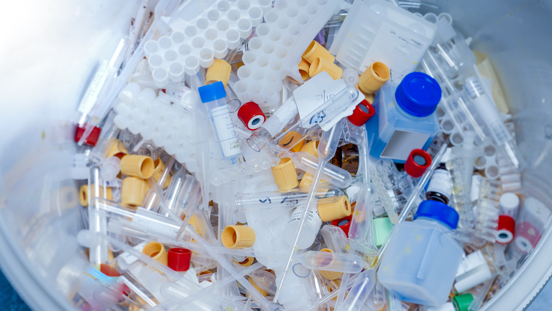 container with assorted plastic waste from lab including phials and bottles