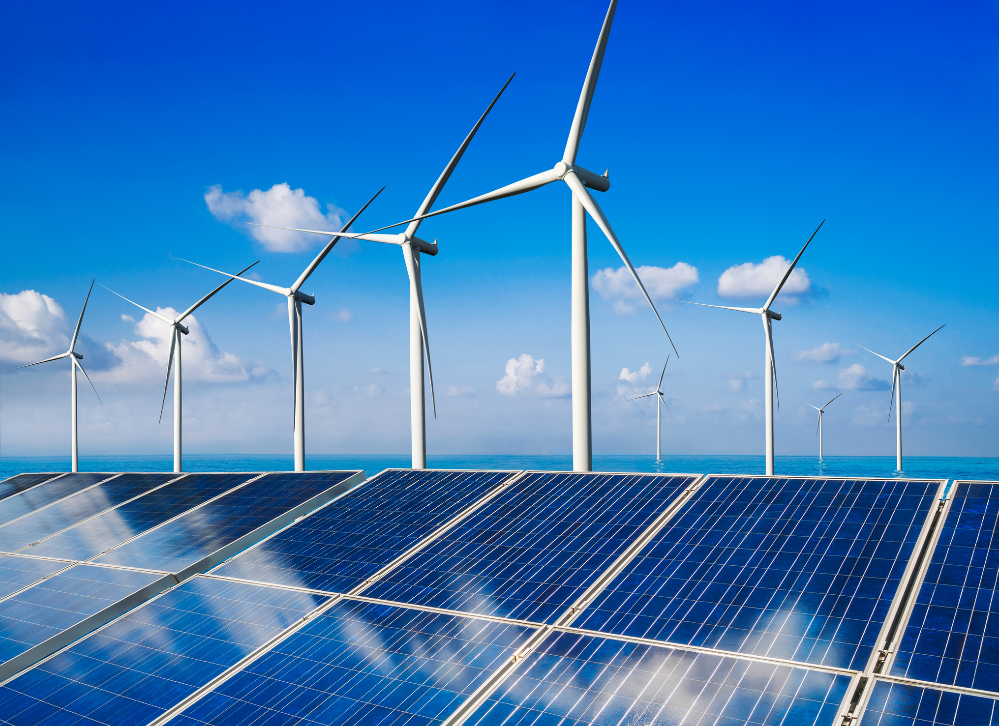 composite image of solar panels, windmills and puffs of cumulus cloud in a blue sky 