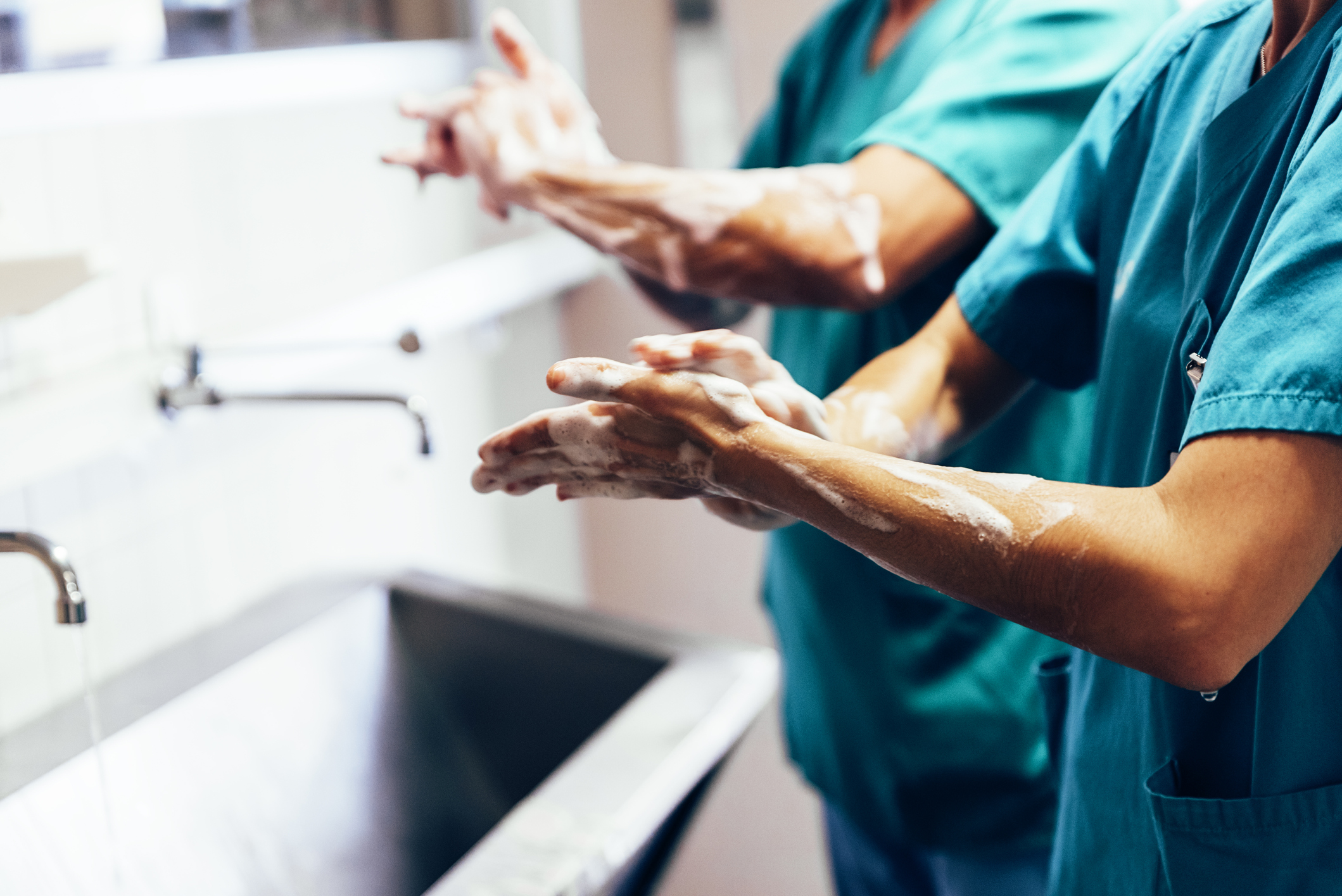 people in scrubs washing their hands in a healthcare facility