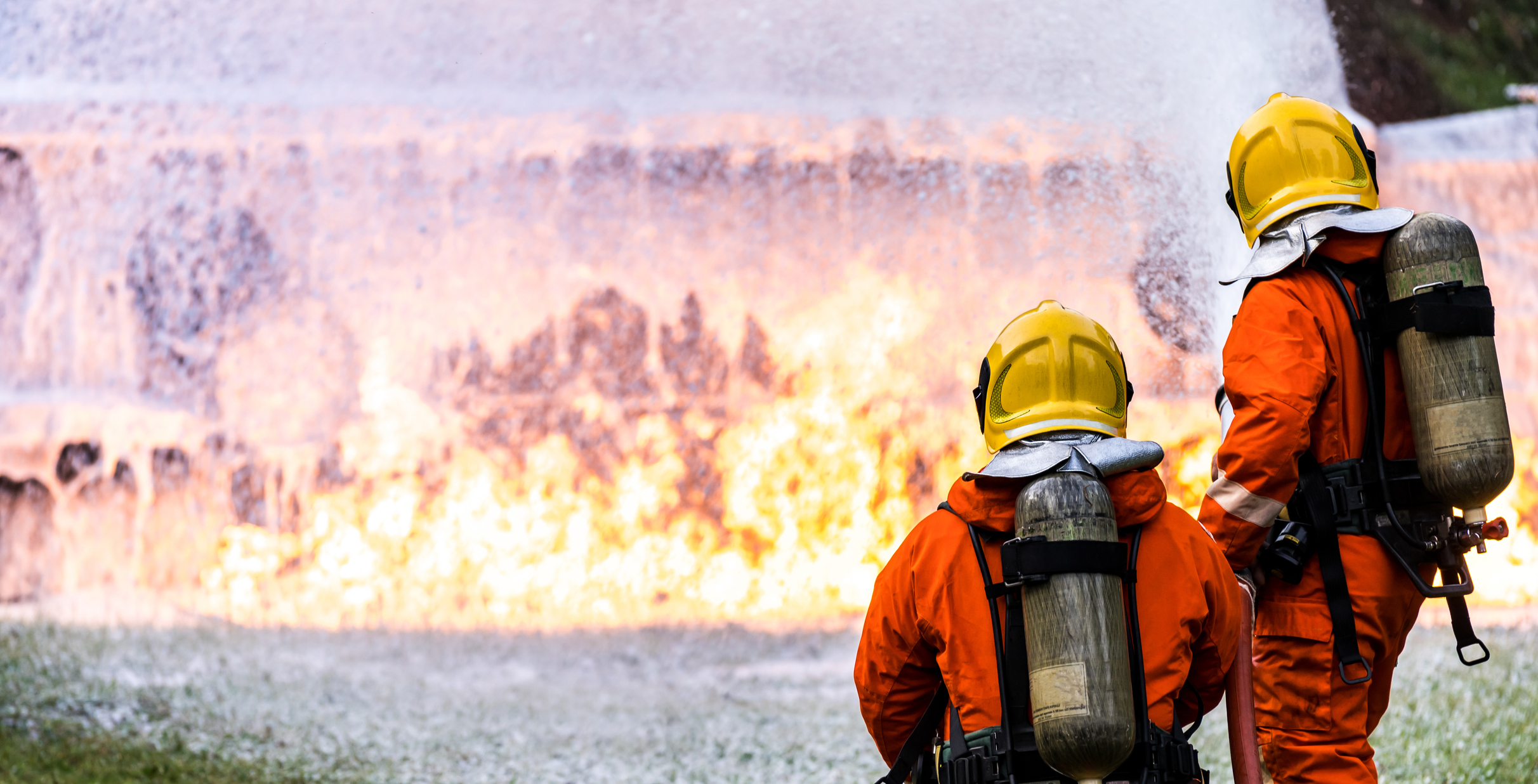 firefighters using foam on a large fire