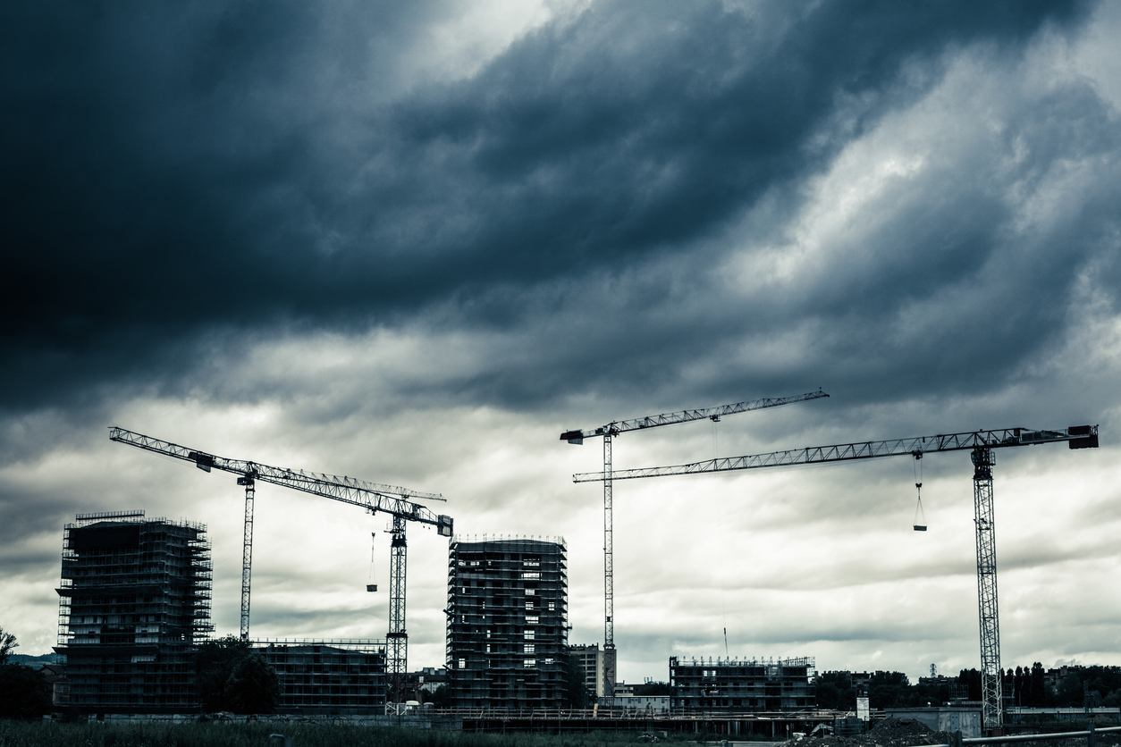 photograph of construction and cranes under stormy sky
