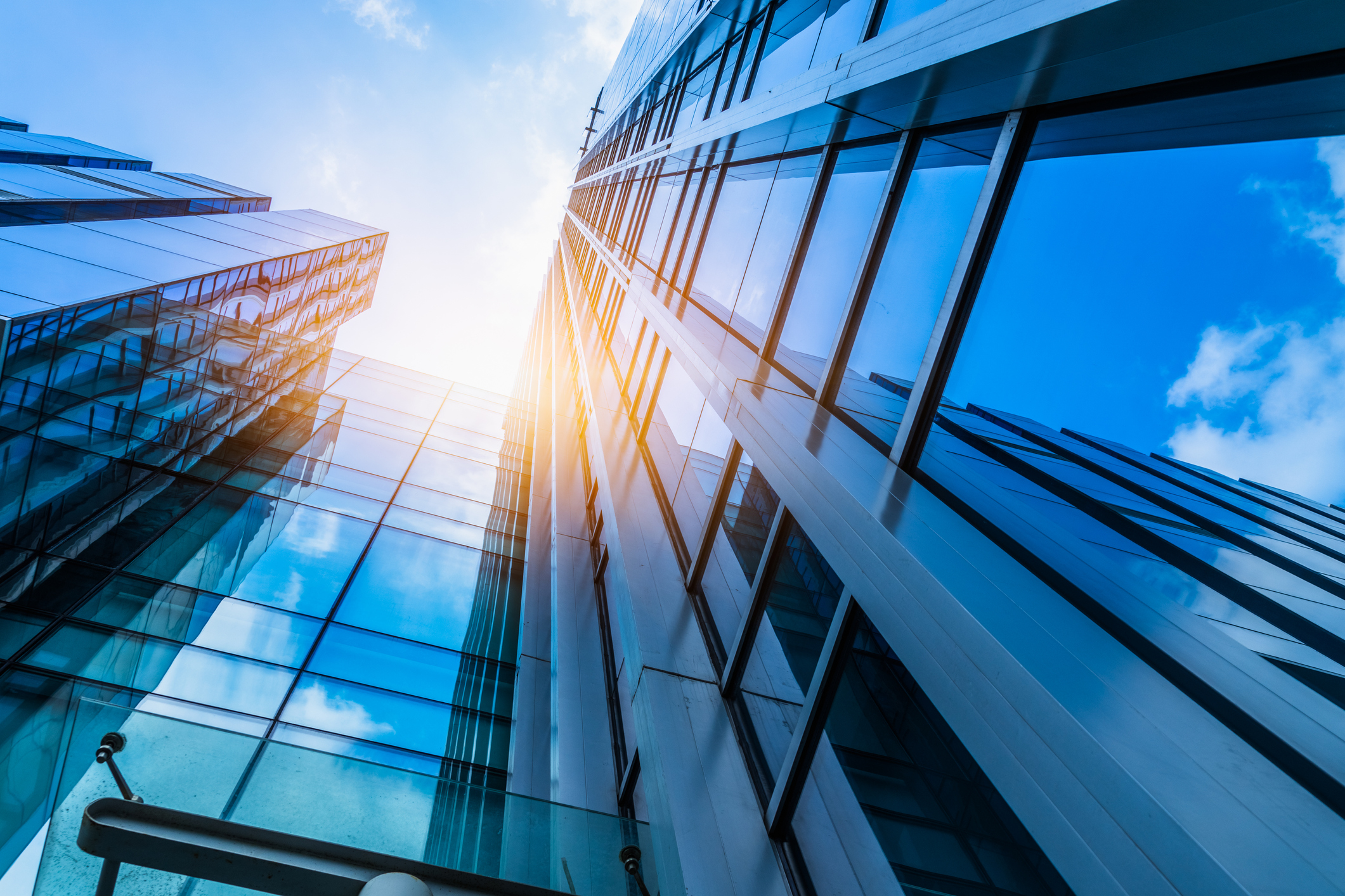 modern multistorey building windows viewed from below with sun shining down
