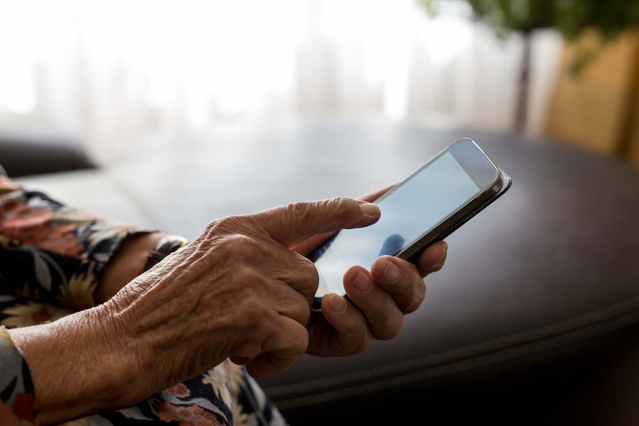 an older person's hands working a smart phone