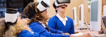 Three students smiling as they try out VR headsets