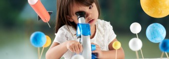 A young girl looking through a microscope surrounded by planets and a rocket on strings