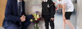 Simon Harris smiling beside two school children outside a classroom