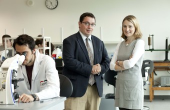 A man and woman standing in a lab among many people working in the lab.