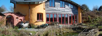 The Hollies Centre for Practical Sustainability building with a man made pond sitting in front of it