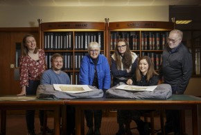 Members of the VOICES team standing in a library at the National Archives, viewing documents