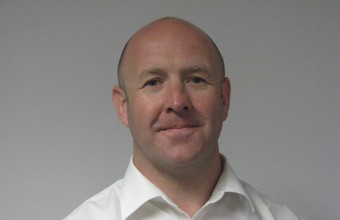 Headshot of a man wearing a white shirt smiling.