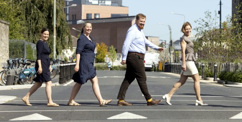 TU Dublin researchers Dr Lorraine D'Arcy and Dr Eoin McGillicuddy stride across a pedestrian crossing with their Societal Impact Champion Caren Gallagher and SFI Scientific Programme Manager Dr Ekaterina Nesterenko