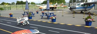 Child toy planes sitting on a fake runway with old aircrafts in the background