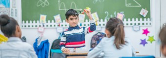 A child in front of a classroom presenting a representation of a chemical compound. 