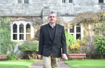 A male walking through the outsides of UCC.