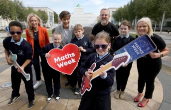 Group of males and females promoting maths week by having fun with cardboard guitars
