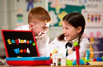 two younger primary school children in their uniform at school surrounded by toys for Engineer week.