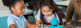 Two young girls in classroom looking interested at an experiment.
