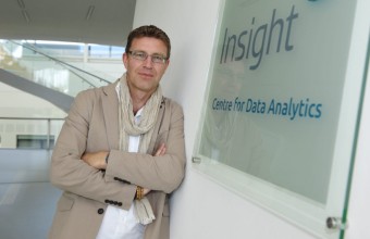 Image of a male leaning up against a Insight Logo from an SFI research centre.