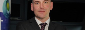 A picture of a man in a dark grey suit and tie.