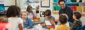 Teacher laughing with students as they cut up plastic for art supplies