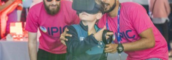 Image of young person with VR headset on and two other people wearing pink IPIC tshirts