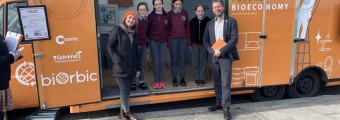 Image of orange bus with people and students posing in front of it