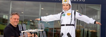 A Child pictured at Aerospace Studies dressed as a astronaut with a older man standing holding a crafted space object.