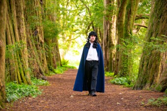 Image of a male walking through a bright green forest.