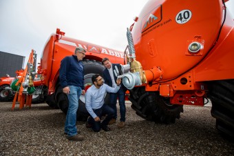 Three men checking out red farm equipment