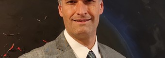 An Image of Dan Kilper in a white shirt, agrey coat and a blue tie