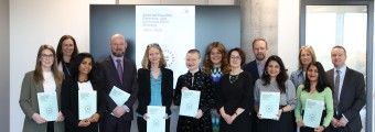 Group picture of SFI staff holding a booklet of SFI's external Equality, Diversity and Inclusion Strategy.