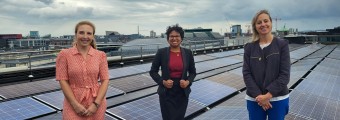 image of team members standing next to solar panels on building roof 