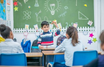 A child in front of a classroom presenting a representation of a chemical compound. 