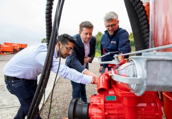 Three men examining farm equipment