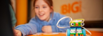 This image shows a young child on a laptop which is located beside a toy
