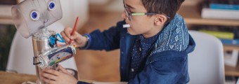 Young boy colouring on a robot