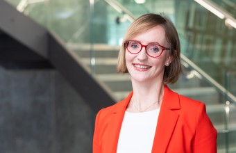 Picture of a women wearing a red blazer with a stairs behind her