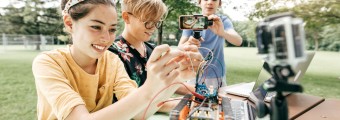 Three students filming the process of setting up robotics using go pros