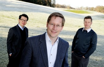 An image of three men standing on a field