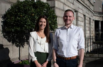 Picture of a Woman standing beside a man with a tree on the background