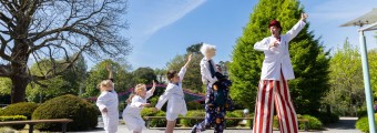 In this image there are 3 children having fun following 2 people dressed up in costumes