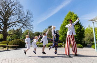 In this image there are 3 children having fun following 2 people dressed up in costumes