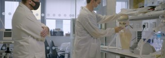 two men dressed in lab coats working on an experiment in a lab