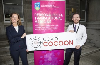 A man and a women holding up up a banner saying "covid cocoon"