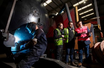 men building and working on farm equipment in a factory