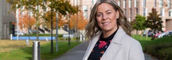 Image of Dr Katriona O'Sullivan standing outdoors in Maynooth University campus. There are buildings and trees in the background. 